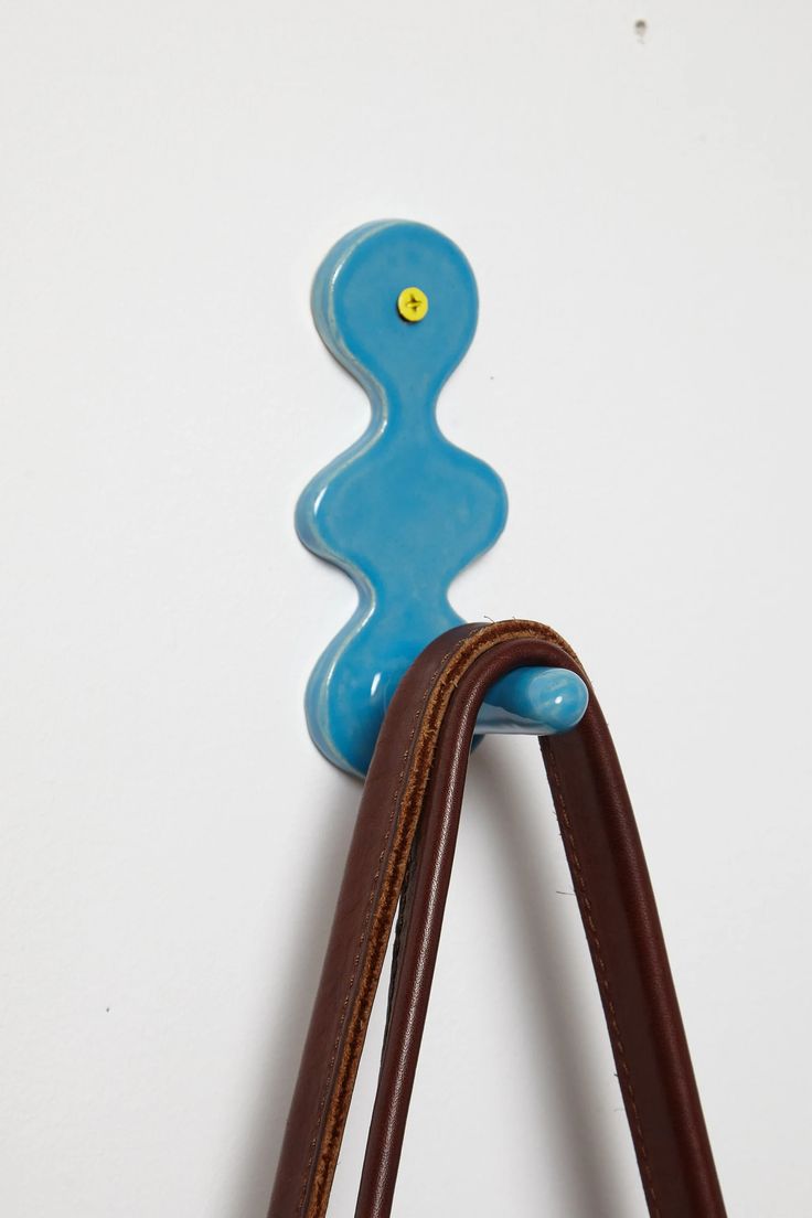 a handbag hanging on the wall with a blue object attached to it's handle