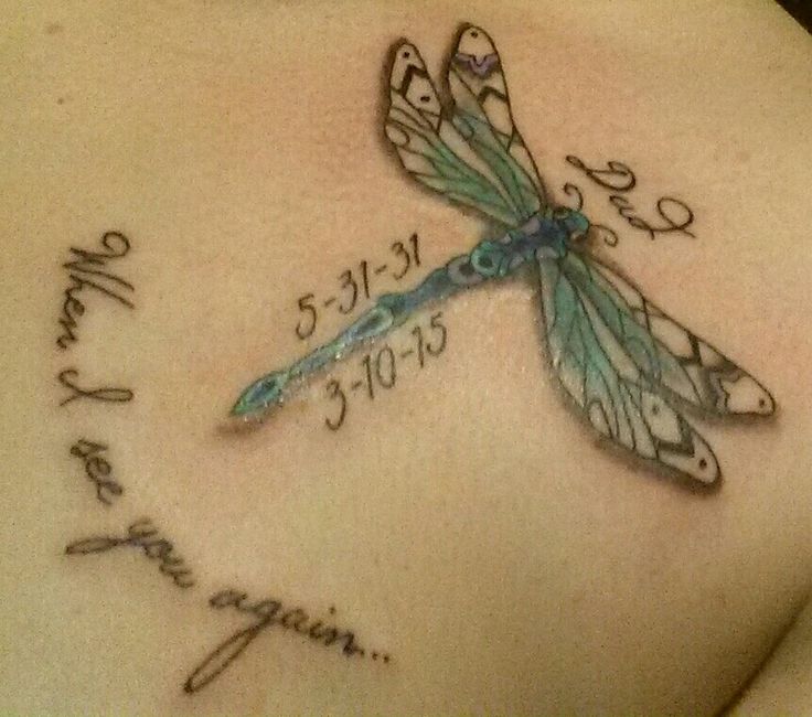 a dragonfly tattoo on the back of a woman's stomach with words written in cursive writing