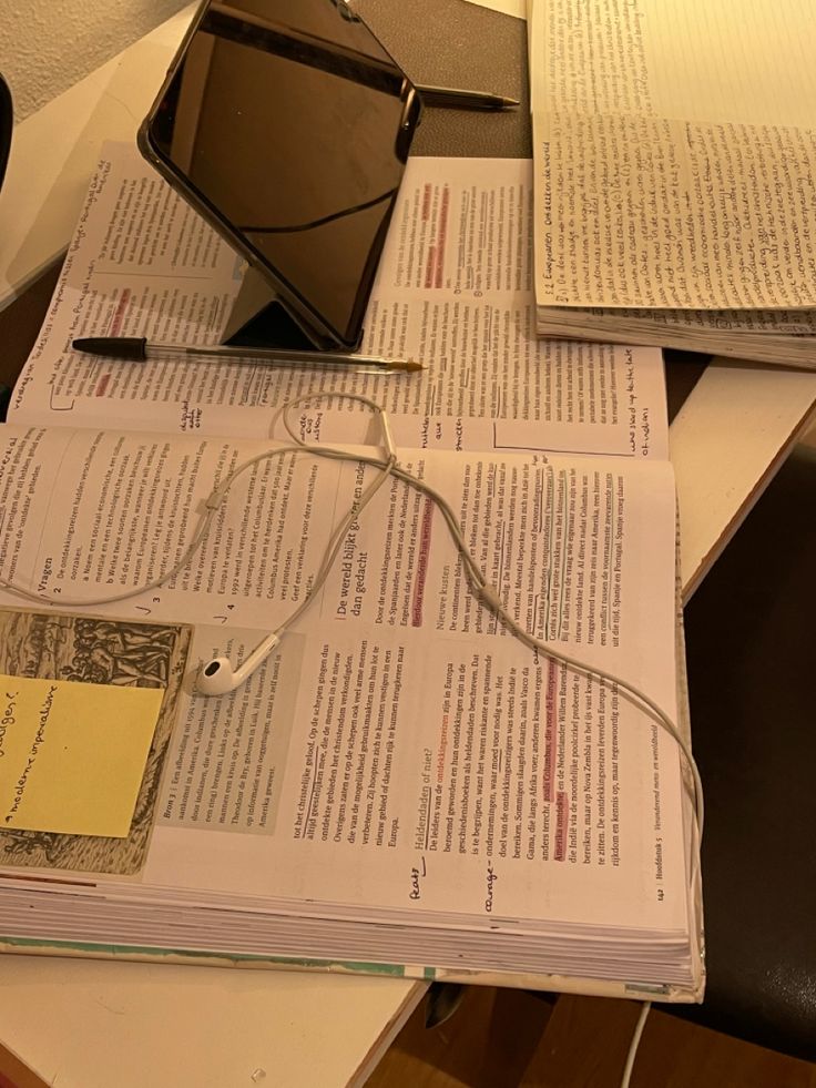 an open book sitting on top of a table next to a computer mouse and headphones