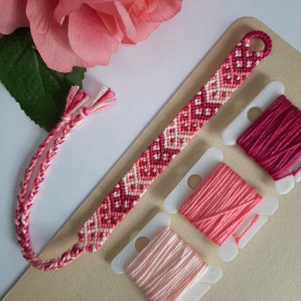 three different types of thread on a table next to a pink rose