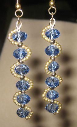 two pairs of earrings with blue and gold beads hanging from the earwires on a table