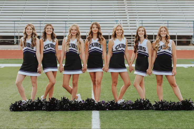 a group of cheerleaders standing on top of a field