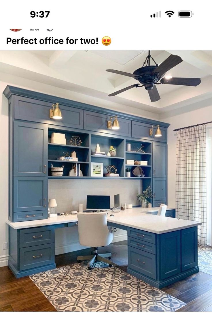 a home office with blue cabinets and a ceiling fan in the middle of the room