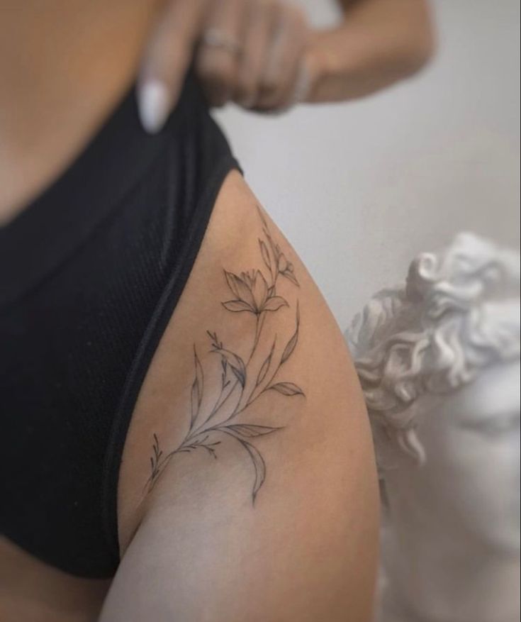 a woman is getting her tattoo done on her thigh with flowers in the back and behind her