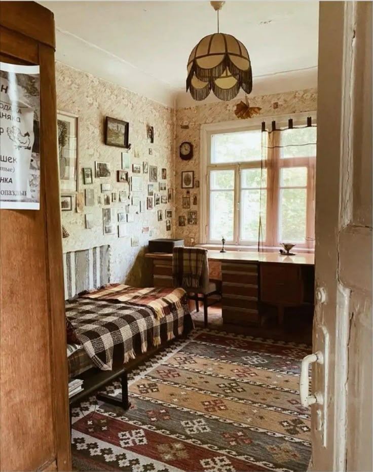 an old fashioned bedroom with two beds and pictures on the wall above them, in front of a window