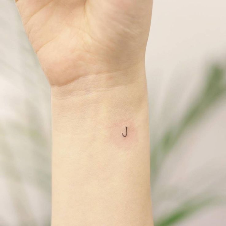 a small letter j tattoo on the wrist