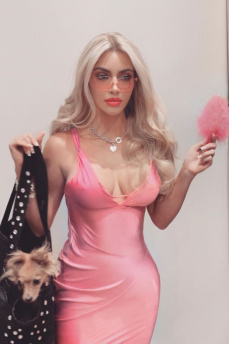 a woman in a pink dress is holding a bag and a stuffed animal on her arm