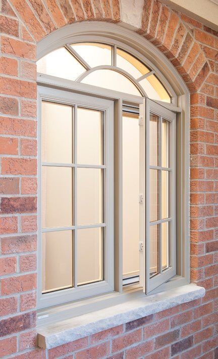 an arched window on the side of a brick building with white trim and glass panes