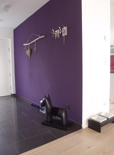 a purple wall in an empty room with sculptures on it