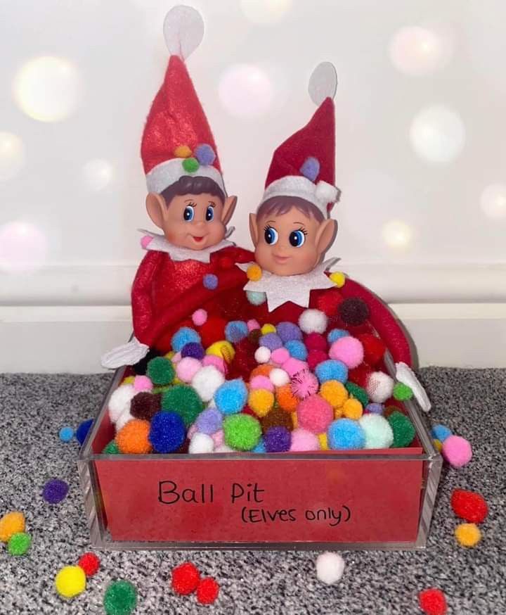 two elfs sitting in a box filled with pom poms