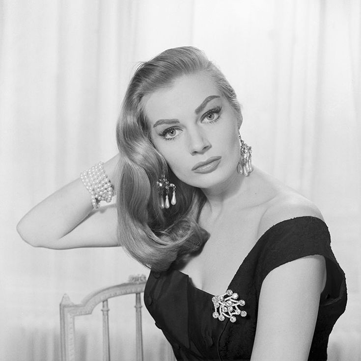 a black and white photo of a woman sitting on a chair with her hair blowing in the wind