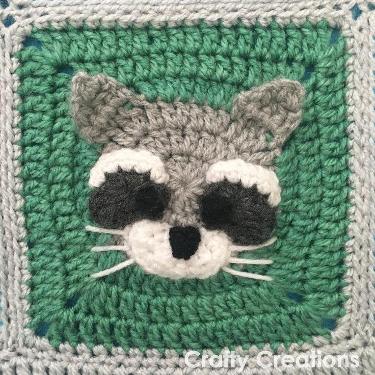 a crocheted square with a raccoon face on it