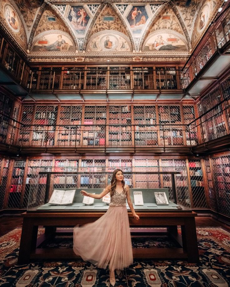 a woman standing in front of a library filled with books