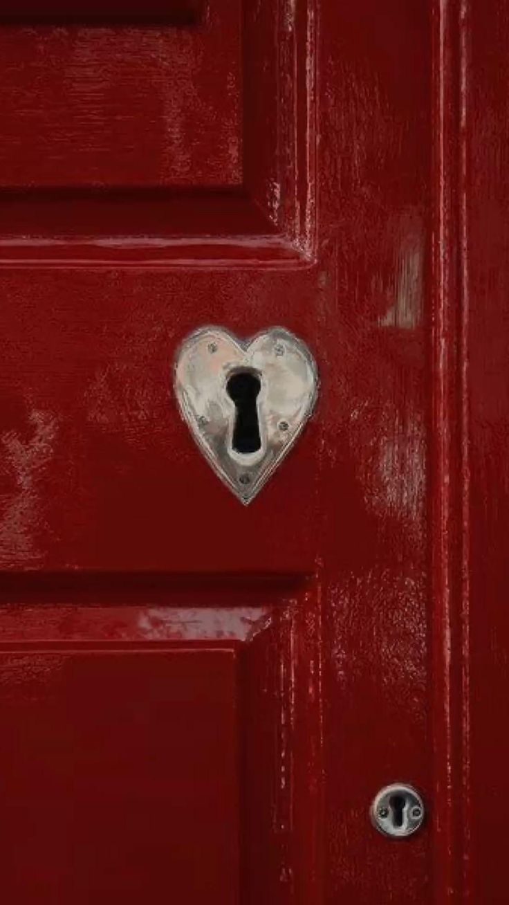 a red door with a heart shaped lock on it's side and a keyhole in the middle