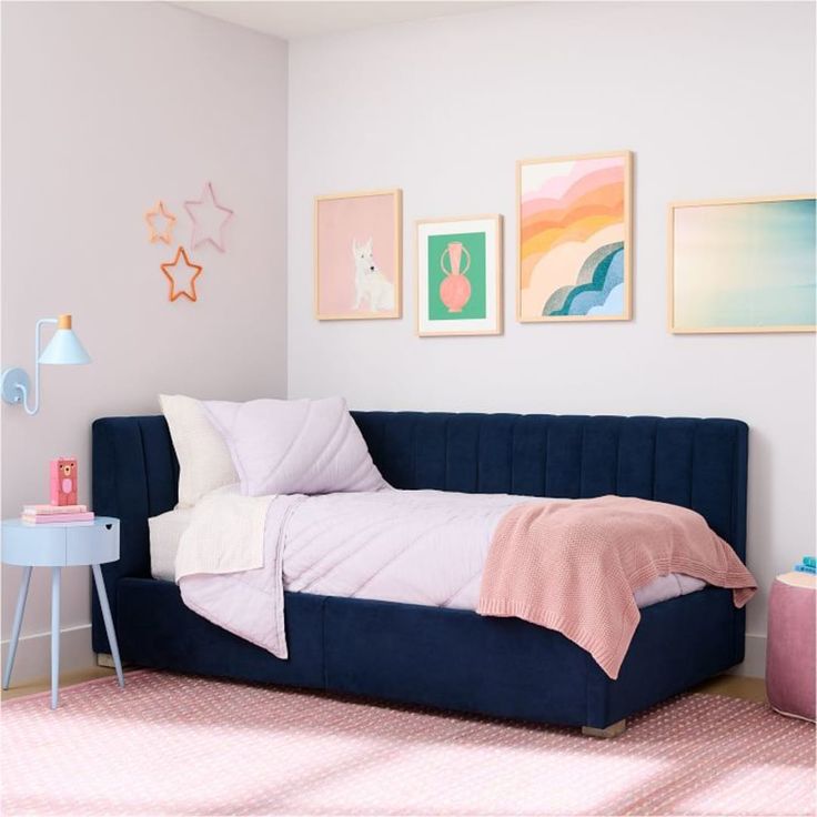 a bedroom with pink, blue and white decor on the wall above the twin bed