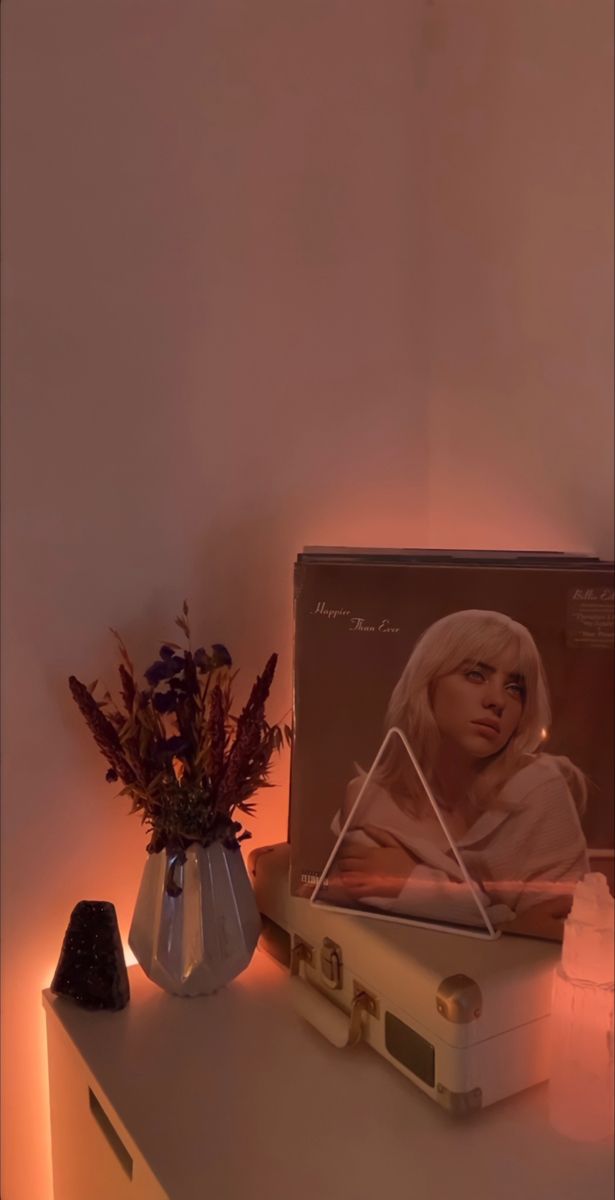 a white suitcase sitting on top of a table next to a vase with flowers