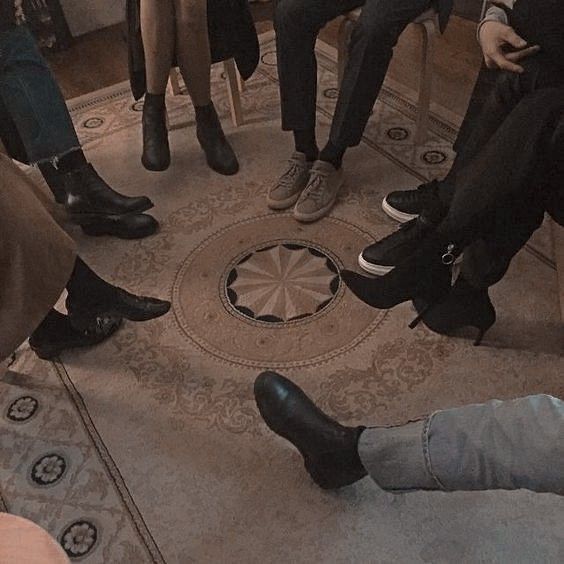 four people sitting in a circle with their feet on the floor and one person wearing black shoes