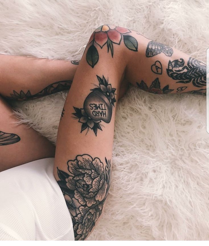 a woman laying on top of a white rug covered in tattoos and leggings