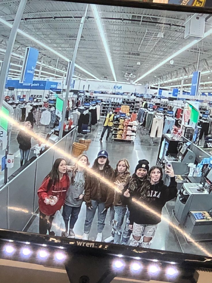 a television screen showing people shopping in a store with their hands up and one person taking a selfie