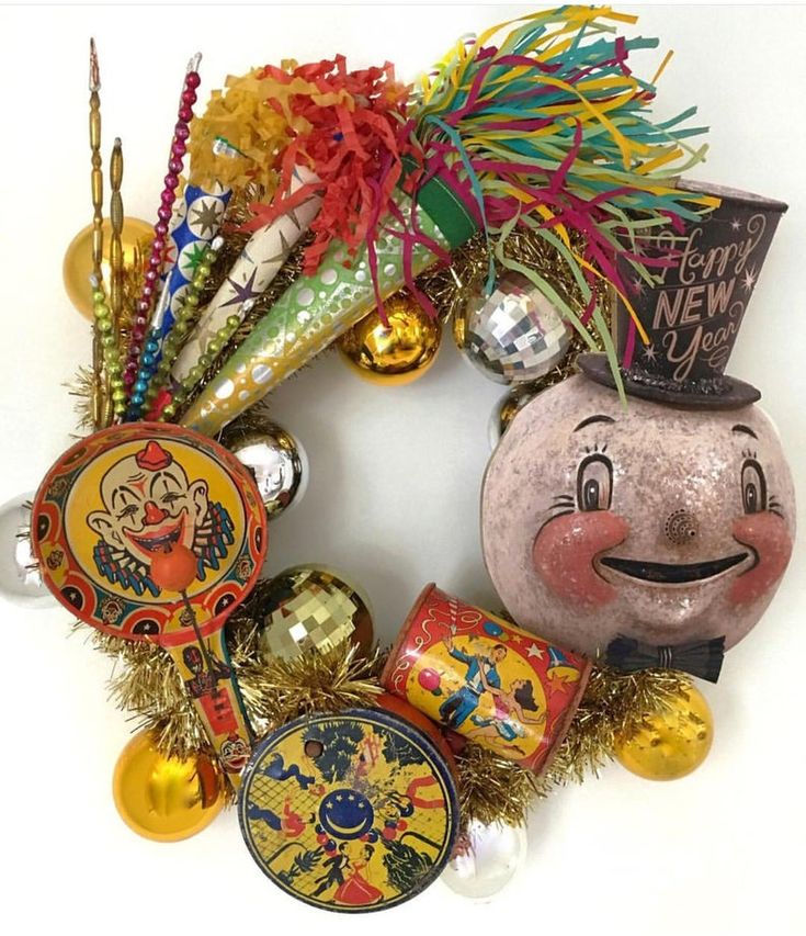 a christmas wreath with ornaments and decorations around it, including a clown face ornament