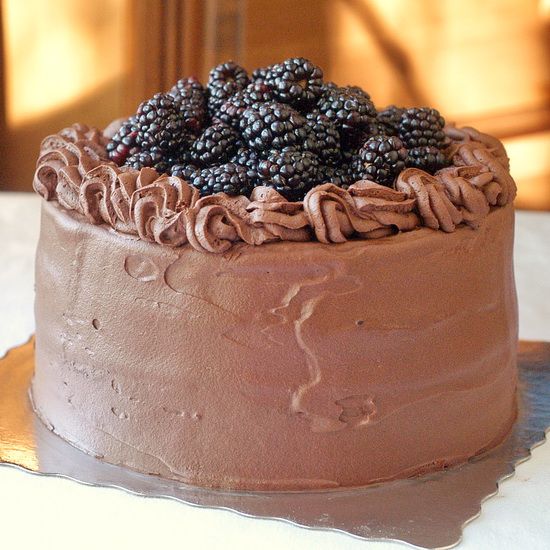 a chocolate cake topped with blackberries on top of a table