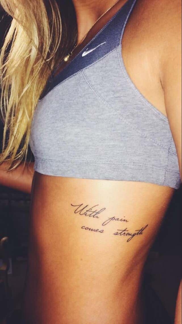 the back of a woman's stomach with a tattoo on her left side and words written in cursive writing