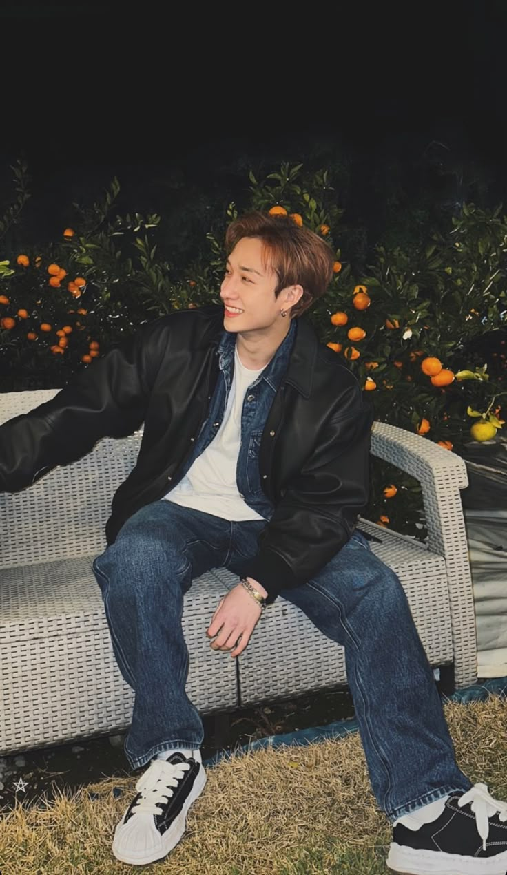 a man sitting on top of a white couch next to an orange tree