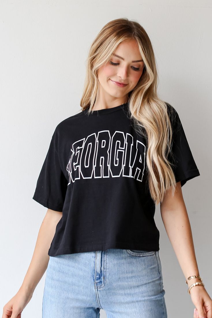 Calling all Dawgs fans, the Black Georgia Block Letter Cropped Tee was made just for you! This comfy tee is designed with a soft and stretchy knit. It features a crew neckline, short sleeves, a relaxed fit, and the word "Georgia" on the front. Style the Black Georgia Block Letter Cropped Tee with your favorite distressed denim and sneakers for the perfect game day look! Soft + Stretchy Knit Fabrication "Georgia" Graphic Crew Neckline Short Sleeves Relaxed Fit 100% Cotton Machine Wash Cold, Tumbl Uga Gameday Outfit, Exclusive Dress, Perfect Game, Gameday Outfit, Cropped Tee, Block Lettering, Comfy Tees, Large Bust, Crop Tee