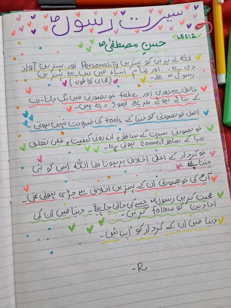 an open notebook with arabic writing on it and colored pencils next to the page