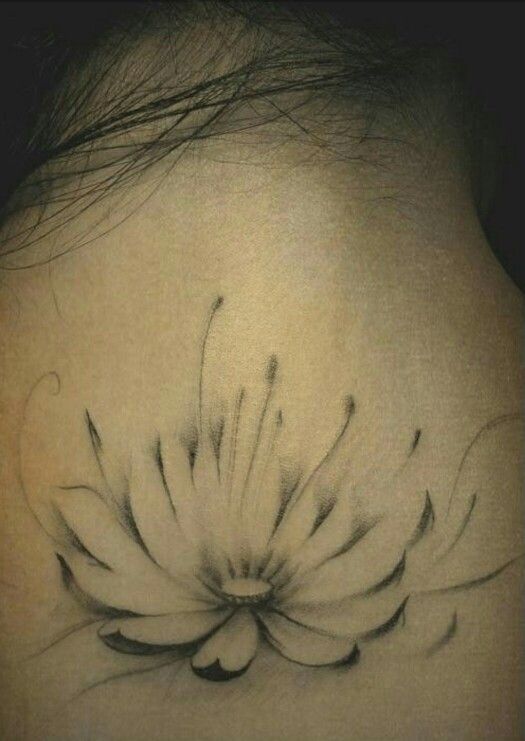 the back of a woman's neck with a flower tattoo on her left side