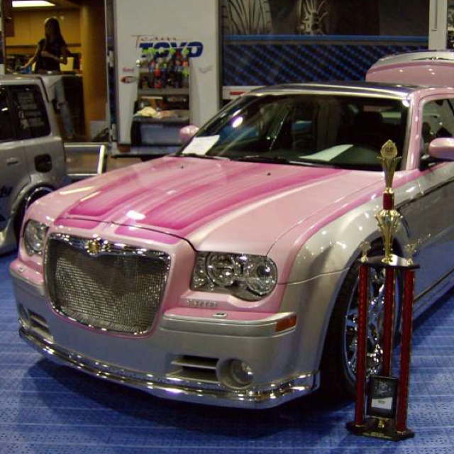 a pink and silver car on display in a showroom