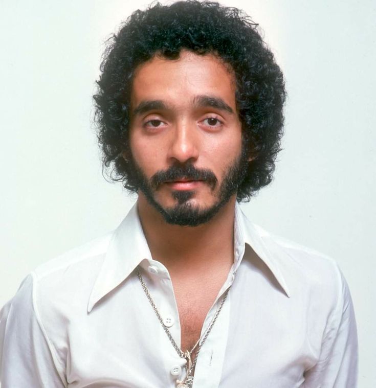 a close up of a person wearing a white shirt and tie with long curly hair