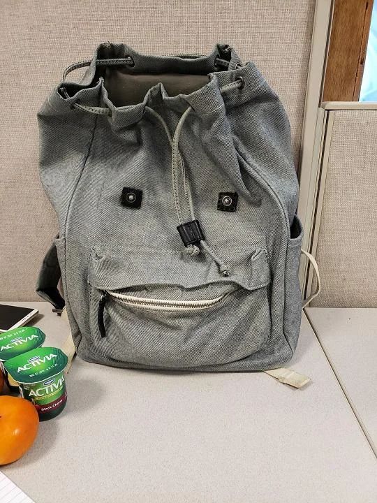 a gray bag sitting on top of a counter next to oranges