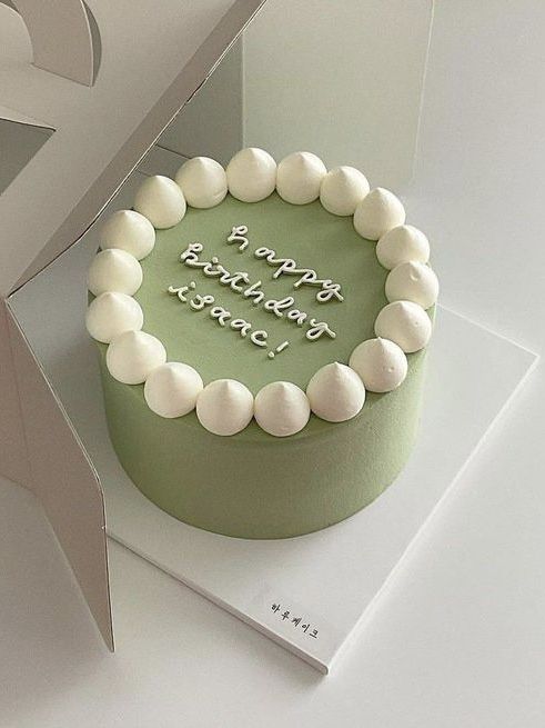 a green birthday cake with white frosting in a box on top of a table