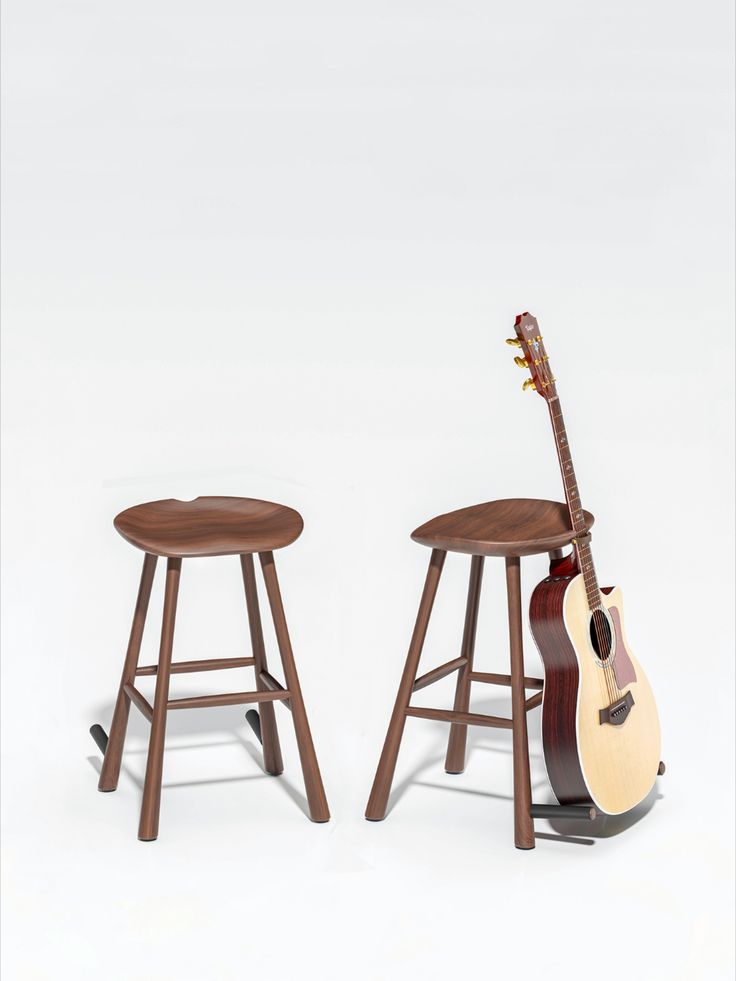 two wooden stools with guitars on them sitting side by side in front of a white background