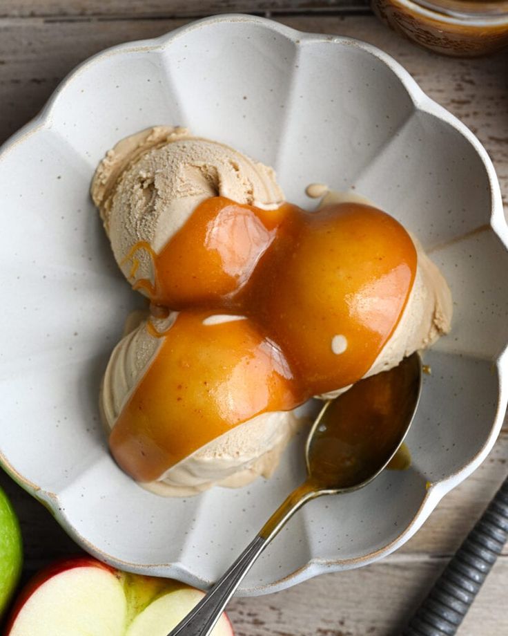 two apples and ice cream in a bowl with spoons