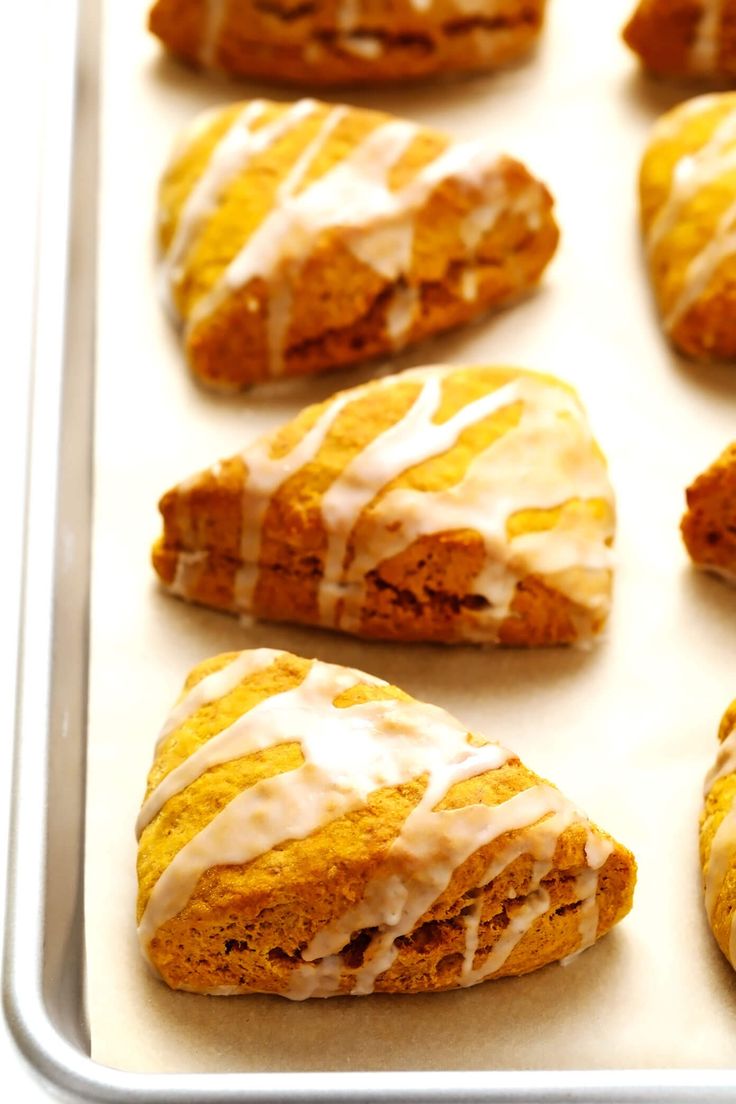 several pastries with icing sitting on a baking sheet in a pan, ready to be baked