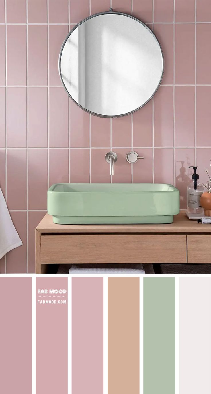 a bathroom with pink and green tiles on the walls, a round mirror above the sink