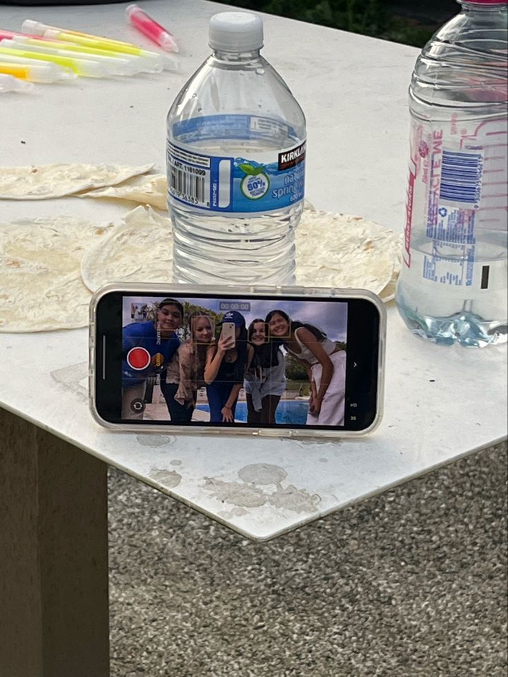 a cell phone sitting on top of a table next to a bottle of bottled water