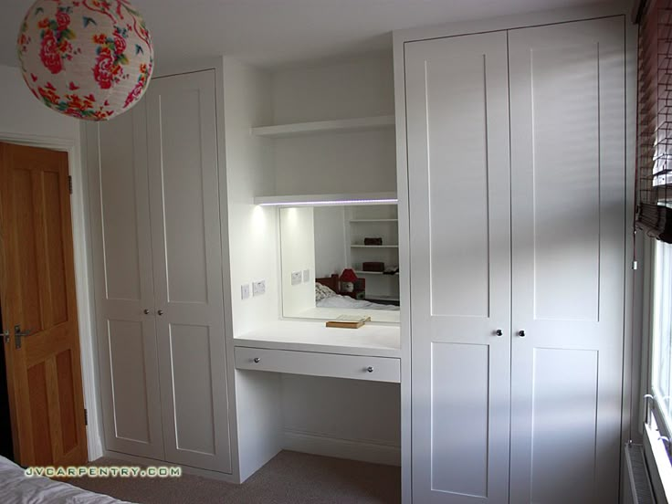 an empty bedroom with white closets and drawers