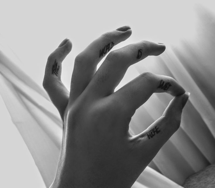 a person's hand with the word love tattooed on their left index and fingers