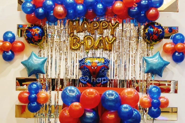 balloons and streamers decorate the entrance to a spiderman themed birthday party with red, blue, and silver decorations