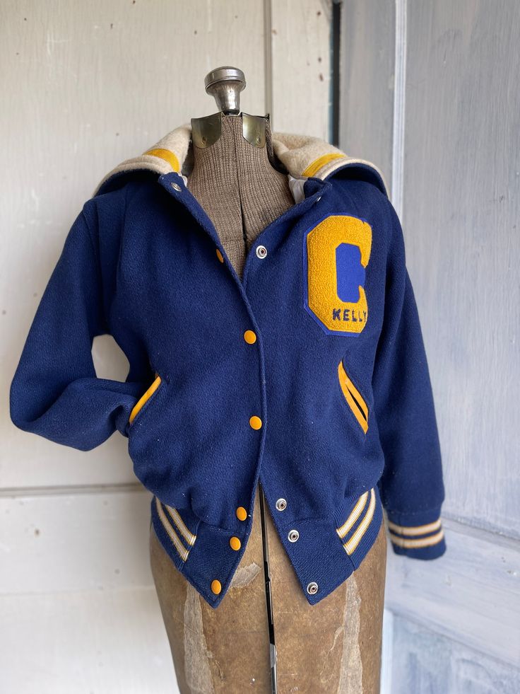 Step back in time with this stylish Vintage Varsity Jacket in vibrant blue and gold. Perfect for showcasing classic collegiate spirit, this retro athletic bomber jacket captures the essence of 1980s sports culture. It's not just a piece of clothing, but a slice of history. - Timeless Style: Features the iconic letterman design with striped ribbing and a snap front closure. - Vibrant Colors: Stand out with the striking blue and gold colorway, perfect for any sporty or casual outfit. - Quality Mat Collegiate Blue Outerwear For Game Day, Vintage Long Sleeve Sport Coat, Vintage Varsity Jacket With Long Sleeves For College, Collegiate Blue Varsity Jacket For Fall, Vintage Long Sleeve Varsity Jacket For College, Vintage Winter Sport Coat For College, Blue Retro Outerwear For Sports Events, Retro Long Sleeve Varsity Jacket For College, Vintage Hooded Varsity Jacket For Winter