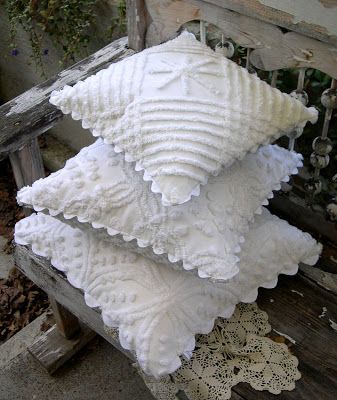 three white decorative pillows stacked on top of each other in front of a wooden bench