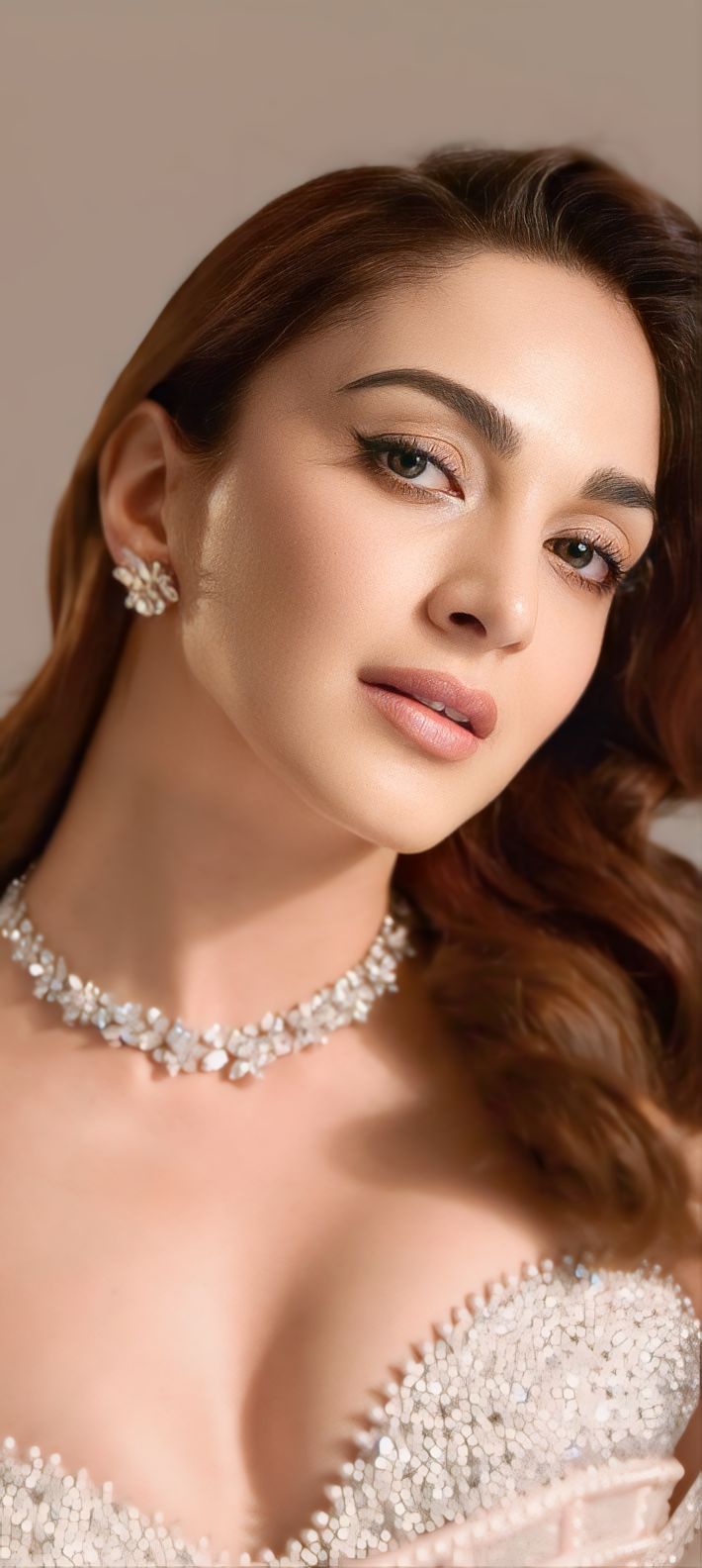 a woman in a wedding dress wearing a necklace and earrings with pearls on the neck