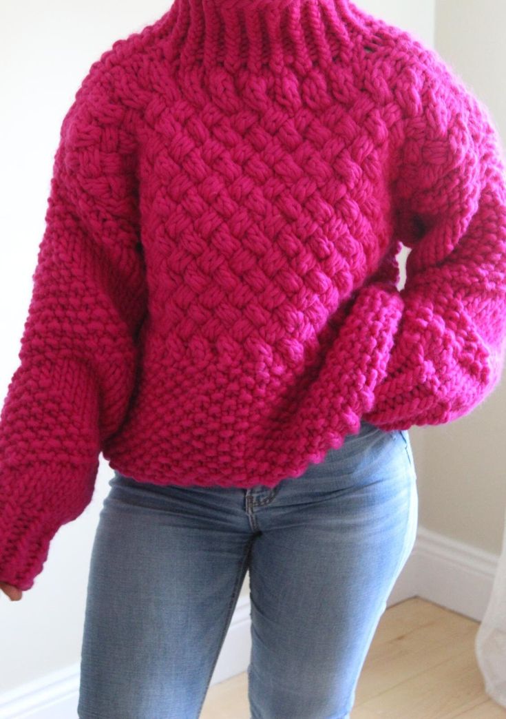 a woman is wearing a pink sweater and jeans