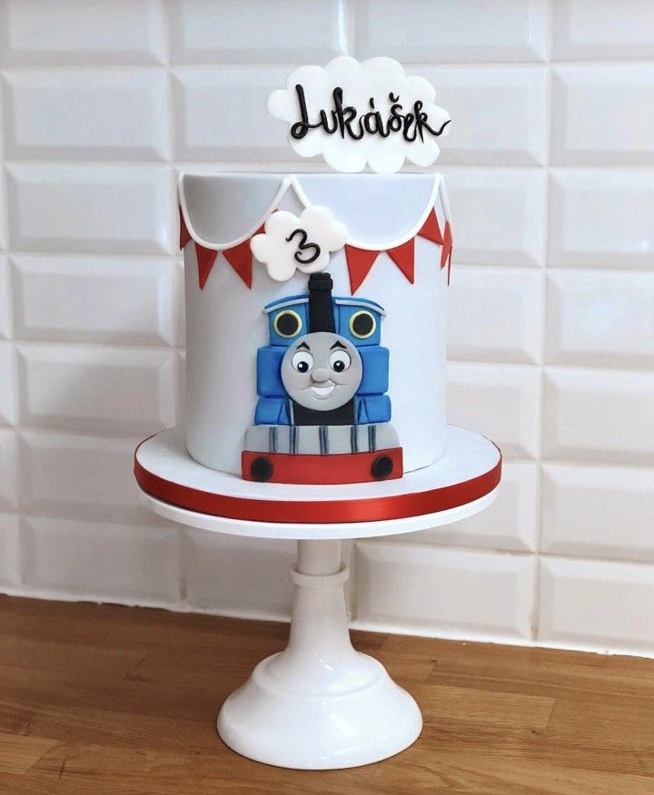 a thomas the train birthday cake on top of a white pedestal with red and blue decorations