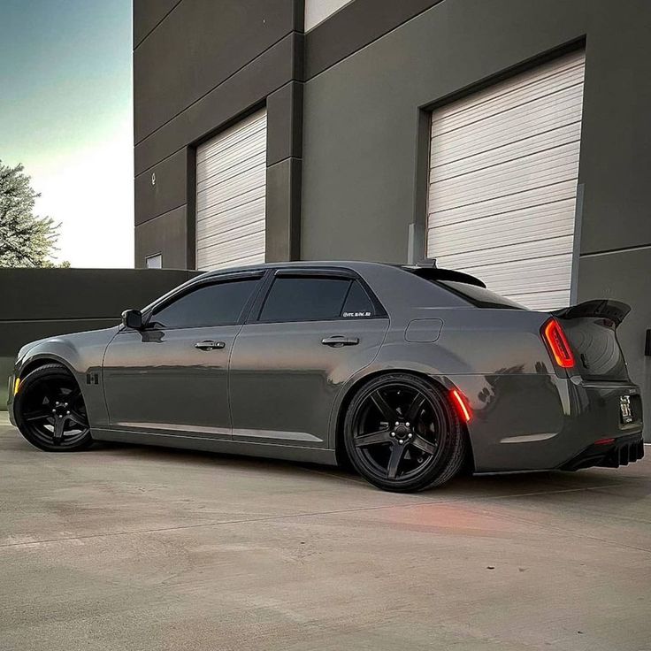 a gray sports car parked in front of a garage door with its rear lights on