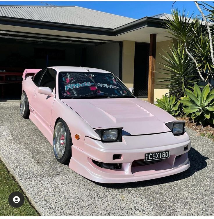 a pink car parked in front of a house