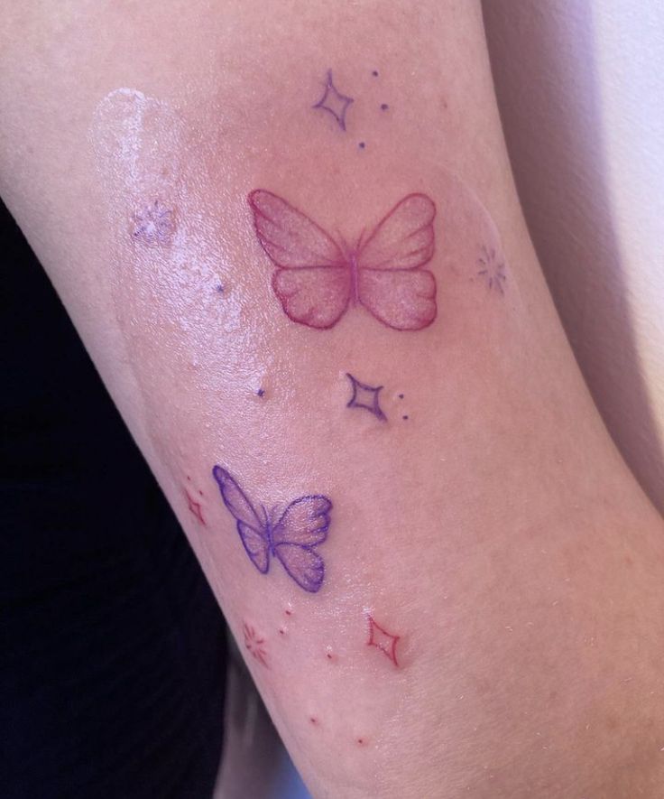 a close up of a person's arm with a tattoo on it and two butterflies